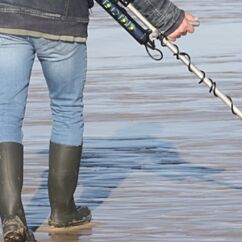 Mann mit Metallsuchgerät sucht bei Ebbe den Strand ab | Von JorGillwald